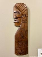 Front view of the cedar carving showing the chief's profile and engraved Indigenous motifs.