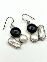 Pair of sterling silver earrings showing black onyx, white freshwater round pearls, and elongated baroque pearls, with hook attachments visible.