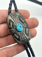 Close-up of the sterling silver Navajo bolo tie clasp showing turquoise stone and engraved design