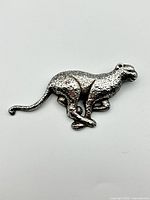 Front view of sterling silver cheetah brooch showing detailed textured spots and running pose