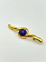 Front angled view of gold plated sterling silver brooch showcasing central oval opal stone with vibrant colors.