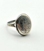 Top side view of the sterling silver ring locket showing the engraved oval cover closed.