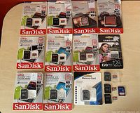 Overview of all SanDisk and Samsung memory cards and adapters shown on table, with retail packaging and loose cards visible.