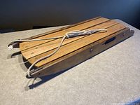 Top-down angled view showing flat wooden slats forming the seat and attached white rope tied at the front.