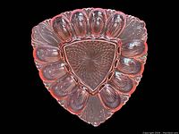 Top-down view of the triangular pink Depression glass devilled egg dish showing raised petal patterns and intricate center design.