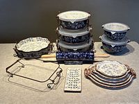 Front view photo of all ceramic bakeware including baking dishes, quiche dish, mixing bowls, serving platters, rolling pin and trivet. Includes metal racks and plastic lids on some items.
