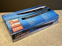 Box of COBY DVD CD HDMI Player showing model and features like upconversion, multi-format support, HDMI compatibility