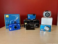 Front view of four Nikon cameras with two boxes and one Vivitar camera in housing on table