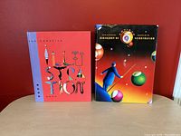 Image showing two hardcover design and illustration books side by side on table against a red wall.