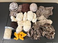 Photo showing collection of vintage natural wool yarn fibres in white, brown, beige and yellow in multiple skeins and loose clumps.