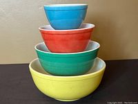 Stacked set of four vintage Pyrex mixing bowls in blue, red, green, and yellow colors.