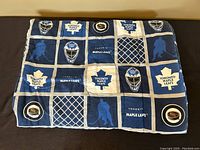 Full view of the vintage Toronto Maple Leafs NHL comforter blanket laid flat, showing its patchwork design of logos and hockey imagery.
