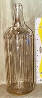 Full side view of the large clear glass vintage Heinz vinegar bottle showing ribbed texture and tall narrow shape with measurement scale for size reference.