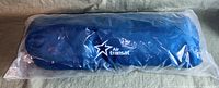 Photo showing front side of the rolled Air Transat travel blanket in original plastic packaging with logo visible.