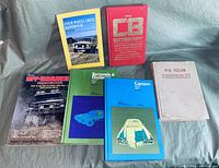 Photo showing six automotive books laid out on a surface, titles visible and readable, including guides to off-roading, specific muscle cars, CB radio dictionary, and vehicle repair.