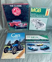 Four automotive books displayed on a surface: The Classic MG, MGB Owners Workshop Manual, Cars in Color, and The MGA MG T MCC Collector's Guide.