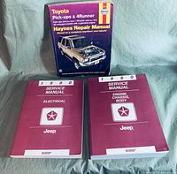 Three automotive service manuals with covers visible: Haynes Toyota Pick-ups & 4Runner Repair Manual, and two 1990 Jeep Service Manuals (Electrical, Engine-Chassis-Body)