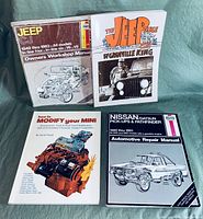 Photo of 4 automotive books featuring Jeep, Mini, and Nissan/Datsun repair manuals with illustrated covers showing engine and vehicle diagrams.