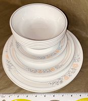 Stack of dinnerware showing bowls, salad plates, and dinner plates with floral pattern and ruler for size reference