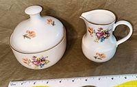 Two-piece Kahla cream and sugar set in white ceramic with floral designs and gold trim, shown with measuring tape for scale.