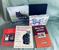 Photo showing five cat books arranged on a green fabric backdrop: Clioster Cats, 2 Cats in a Box, Lady Anne Ives's Cats Birthday Books, The Cat Lover's Dictionary, and Kittens, Cats, and Crime.