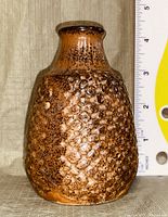 Front view of small brown ceramic vase with textured dot pattern and scale to show size approx. 4.5 inches tall