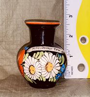 Small ceramic vase with dark brown base, colorful hand-painted flowers and inscription 'HORSOVSKY TYN'. Measuring about 3 inches tall.