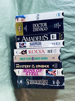 Photo showing 9 VHS tapes stacked side by side with titles visible on spines.