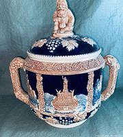 Front view of tureen showing Niederwald monument relief design and ornate lid figurine.
