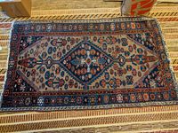 Full view of the Oriental rug laid on the floor showing the geometric and floral central medallion design with predominantly blue and beige colors.