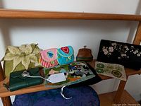 Overall collection of assorted bags, wallets, and purses showing variety of colors, materials, and styles on wooden shelf
