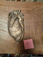 Top view of bronze Art Nouveau dish with nude female figure design showing overall shape and sculptural relief detail.