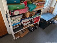 Wide view of the white bookcase with various paper goods and supplies stacked on shelves.