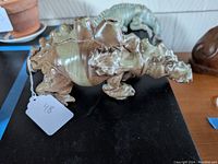 Side view of a glazed ceramic dragon-shaped candle holder with candle holes on the back and detailed texture