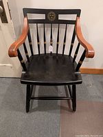 Front view of the Harvard chair showing black finish, natural wood armrests, and Harvard seal on the backrest.