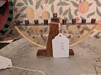 Curved Hanukkah menorah with clear resin panel containing pressed flowers and brass candle holders, standing on a wood base.