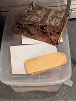 Clear plastic tote containing rolled posters, envelopes, and loose papers