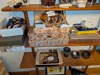 Overview of floral box and wooden shelf with assorted jewelry boxes and baskets