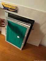 Photo showing stacked Arches watercolor pads with green front covers and black sketch pads behind.