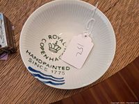 Porcelain bowl interior showing Royal Copenhagen handpainted brand markings and blue waves at rim.