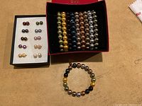 Image showing boxed set of matching pearl-style stud earrings and six bracelets with metallic pearl-like beads in various hues.