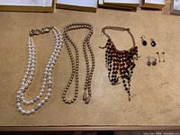 Full lot image with all necklaces and earrings visible on a table.