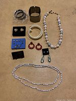 Full view of all costume jewelry pieces arranged on a beige surface showing necklaces, bracelets, and earrings.