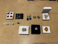 Collection of assorted costume jewelry including earrings, rings, and a necklace with pendant arranged on beige surface