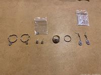 Full view of all jewelry items on surface showing 7 pieces: 4 earrings (2 pairs) and 3 rings.