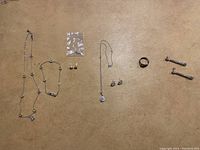 Full view of all jewelry items including two necklaces, bracelet, ring, two pairs of stud earrings, and one pair of dangling earrings.