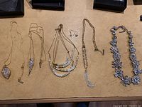 Overview of necklaces and earrings laid out showing all items in lot
