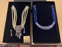 Both Heidi Daus jewelry pieces displayed in black presentation boxes side by side.