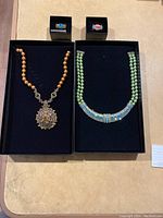 Overview of two necklaces and two rings displayed in boxes