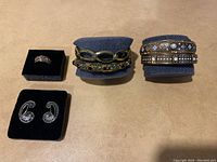 Top view of the full lot showing two bracelets on blue cushions and a ring plus earrings on black velvet pads.